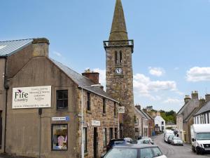 an old building with a clock tower on a street at Little Ingas Cottage in Strathmiglo