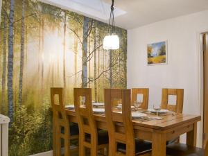 a dining room with a table with chairs and a forest mural at Chartfield in Windermere