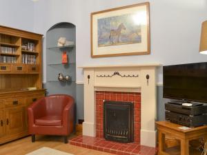 a living room with a fireplace and a chair at Chartfield in Windermere