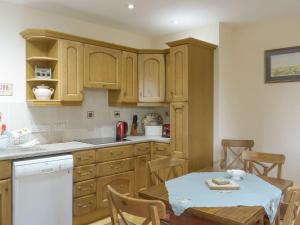 a kitchen with wooden cabinets and a table and chairs at Cluniter Cottage in Innellan