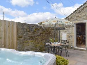 un patio con bañera de hidromasaje y sombrilla en One Uk33732, en Cartworth