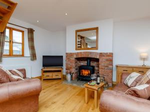 a living room with a fireplace and a tv at The Old Laundry - Uk12136 in Hewelsfield