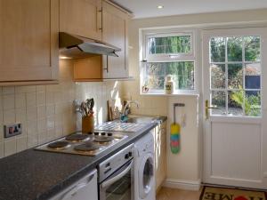 a kitchen with a stove top oven next to a window at Chesterton Cottage in Miningsby