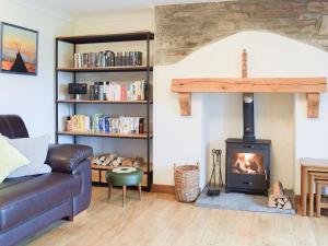 sala de estar con sofá y estufa de leña en Castle Hill Cottage, en Ferryside