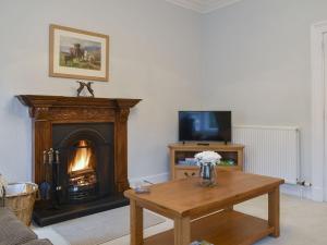 a living room with a fireplace and a wooden table at West Lodge in Banchory