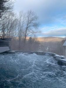 bañera de hidromasaje llena de agua con nieve y árboles en 5 Bedroom House on Hunter Mountain w large 8 Person Hot Tub, Very Private, en Lanesville