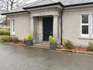 a house with a black door and two potted plants at West Lodge in Banchory