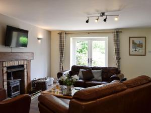 a living room with a couch and a fireplace at The Brewers Cottage in Mauchline