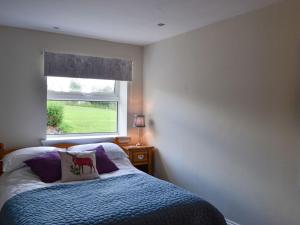 1 dormitorio con cama y ventana en The Brewers Cottage, en Mauchline