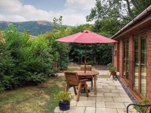 - une table en bois avec un parasol sur la terrasse dans l'établissement Little Acorns, à Great Malvern