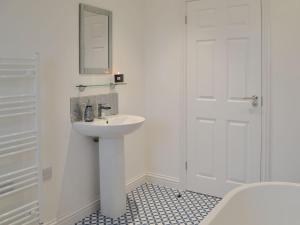 uma casa de banho branca com um lavatório e um espelho em West Kilbride em Pollachar