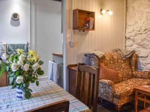 a room with a table and a chair and a vase of flowers at Bwth Carron in Barmouth