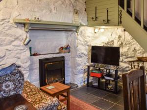 a living room with a stone wall with a fireplace at Bwth Carron in Barmouth
