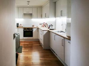 uma cozinha branca com pisos em madeira e armários brancos em Kilbowie Retreat em Oban