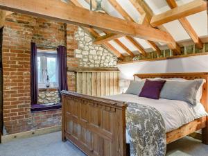 a bedroom with a wooden bed in a brick wall at Honey Pots in Foulden