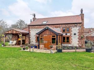 a brick house with a deck and a patio at Honey Pots in Foulden