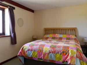 a bedroom with a bed with a colorful quilt at Stable Cottage - Uk12088 in Saint Endellion