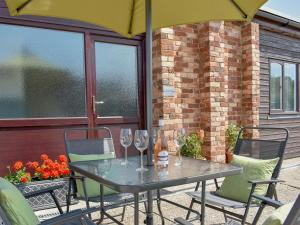 a table and chairs with wine glasses and an umbrella at Serendipity in Ferndown