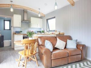 a living room with a brown couch and a table at Moor Hen Shepherd Hut - Uk33888 in Cullompton
