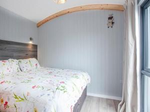 a bedroom with a bed with a floral comforter at Moor Hen Shepherd Hut - Uk33888 in Cullompton