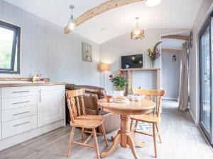 a kitchen and dining room with a table and chairs at Moor Hen Shepherd Hut - Uk33888 in Cullompton