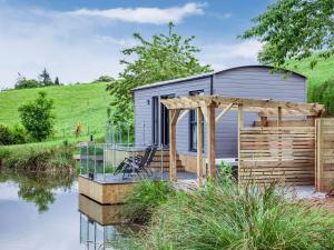 a tiny house sitting on the side of a river at Moor Hen Shepherd Hut - Uk33888 in Cullompton