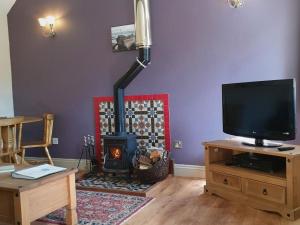 a living room with a fireplace and a tv at Stables Cottage in Garton