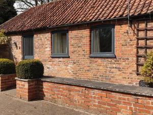 a brick house with two windows and a brick wall at Stables Cottage in Garton