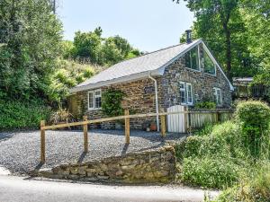 a stone house with a wooden fence in front of it at Woodland Retreat in Washaway