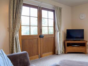 a living room with a door and a television at Walkers Lodge in Hampton Bishop