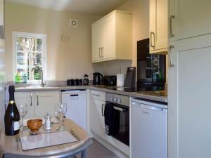 a kitchen with white cabinets and a table with wine glasses at Walkers Lodge in Hampton Bishop