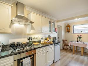 uma cozinha com armários brancos e um forno com placa de fogão em Berwood Cottage em Epworth