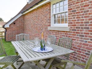 a wooden picnic table with chairs in front of a brick building at Puxton Lodge in Fordwich