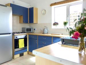 a kitchen with blue cabinets and a white refrigerator at Driftwood House in Sheringham
