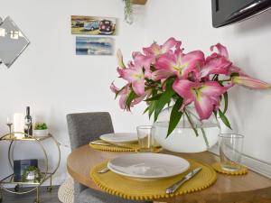 a table with plates and a vase of pink flowers at Lawn Vista Cabin in Barnstaple