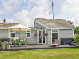 a small house with a patio and an umbrella at Lawn Vista Cabin in Barnstaple