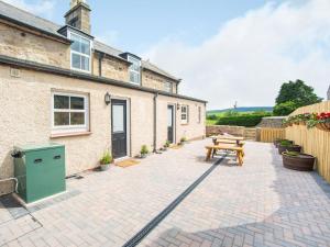 a patio with a wooden bench and a house at Flossys House -uk35020 in Chatton