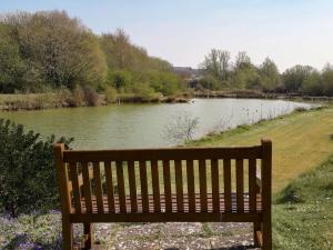 a wooden bench sitting next to a river at Herons Nest in Bourton on the Water