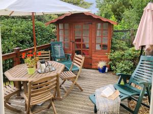 a wooden deck with a table and chairs and a shed at The Swallows in Roche