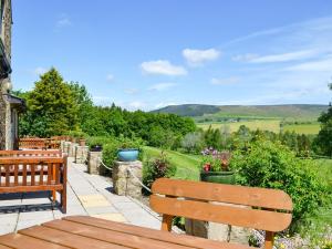 a patio with two benches and a view of the hills at Kestrel View in Skipton