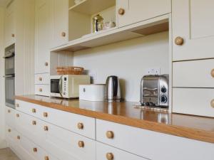 a kitchen with white cabinets and a counter with a microwave at Coachmans Close in Milverton