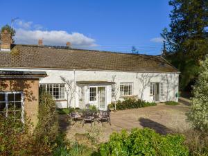 una casa de campo blanca con sillas y una mesa frente a ella en Coachmans Close, en Milverton