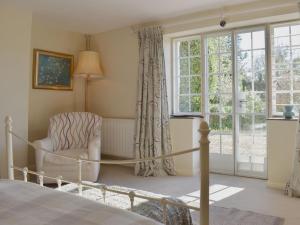 a bedroom with a bed and a chair and a window at Coachmans Close in Milverton