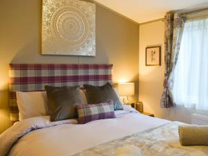 a bedroom with a large white bed with pillows at Riverside Lodge in Auchterarder