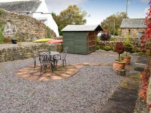 a patio with a table and chairs and a shed at Swallow Barn in Torpenhow