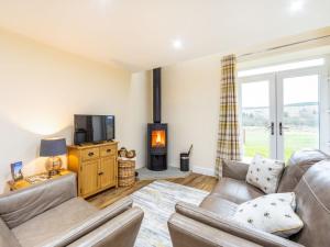 a living room with a couch and a tv and a fireplace at Ferny Rigg Byre - Uk3326 in Falstone