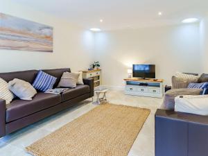 a living room with a brown couch and a tv at Ty Draenog - Uk31653 in New Quay
