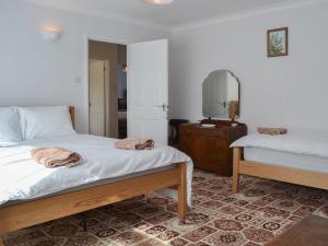 a bedroom with two beds and a dresser and a mirror at The Old Creamery in Witheridge