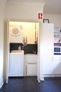 une cuisine avec des armoires blanches et une laveuse et une sécheuse dans l'établissement Lotte's Cottage, à Broken Hill 15 autres photos