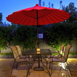 een tafel met een rode parasol op een patio bij Lotte's Cottage in Broken Hill